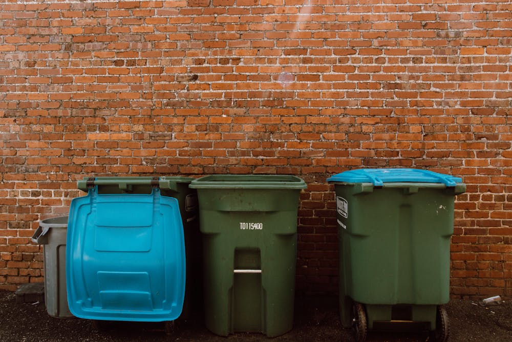 Three Large Bins Outside Against A Brick Wall