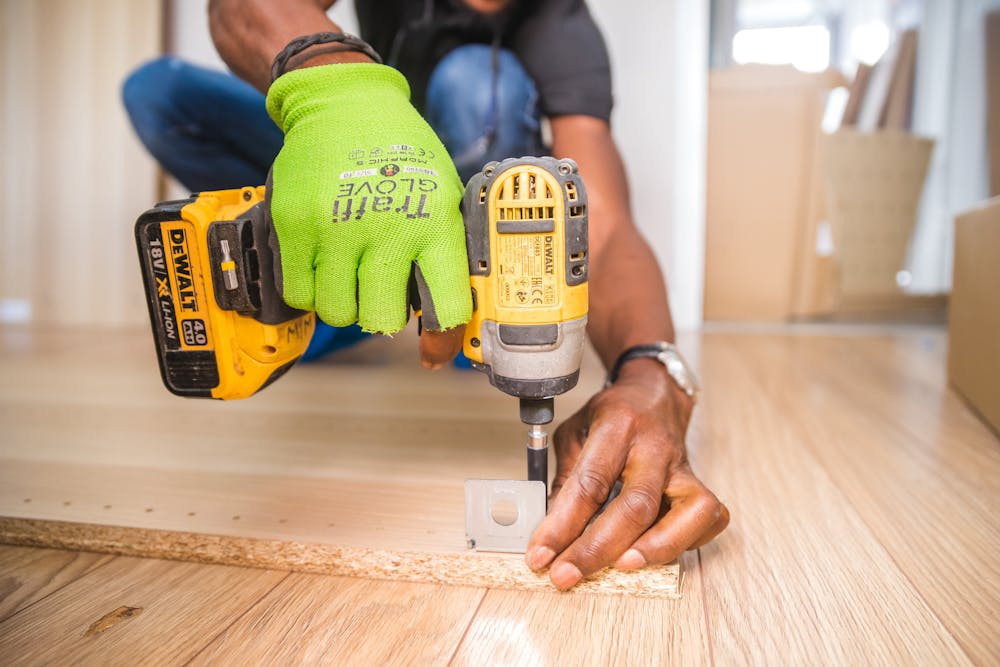 A Man Drilling A Piece Of Wood With A Hand Drill