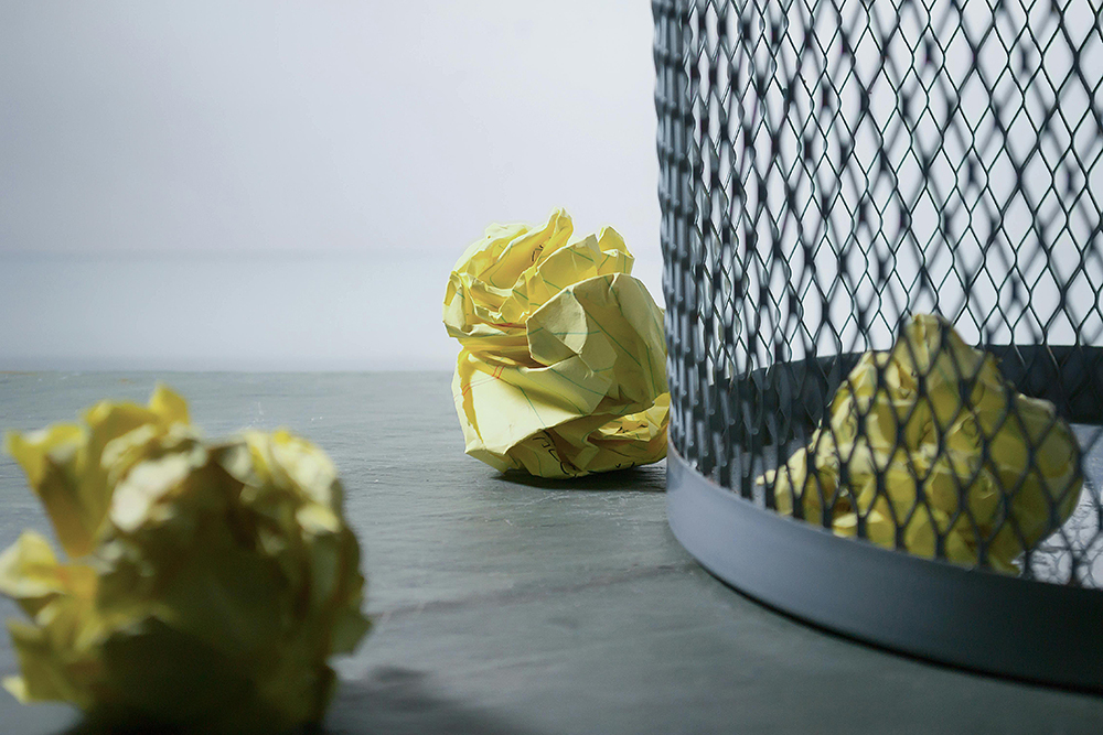 A Waste Paper Basket With Waste Paper Inside And Outside Of It