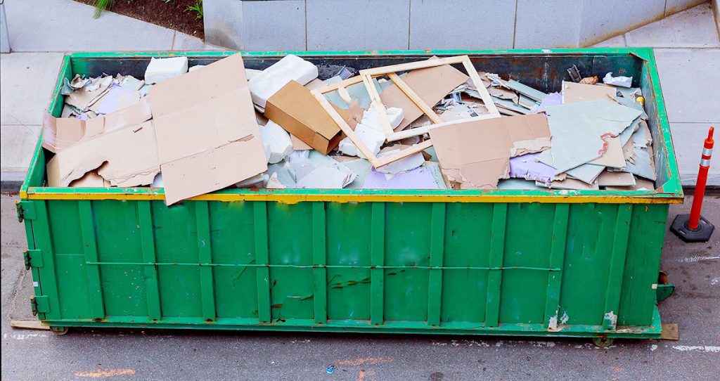 A large green skip bin filled with demolition waste
