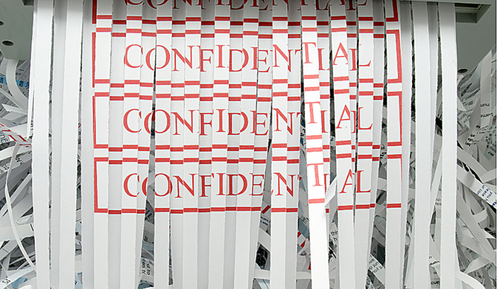 A piece of paper featuring the words "confidential" being put through a paper shredder