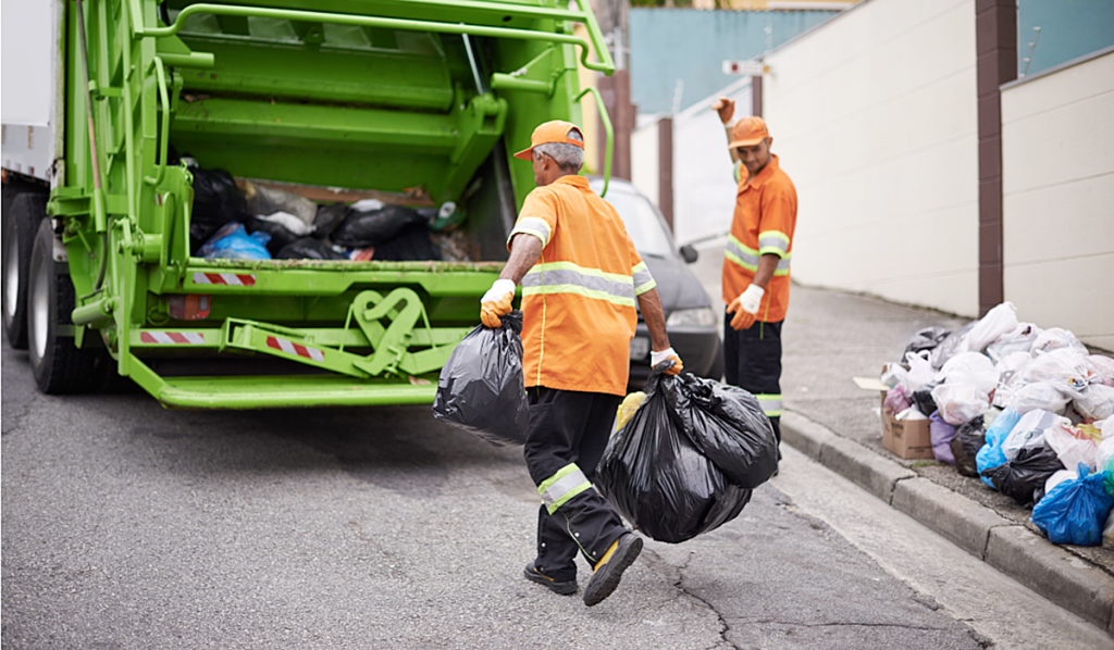 Two men loading a garbage truck on the street