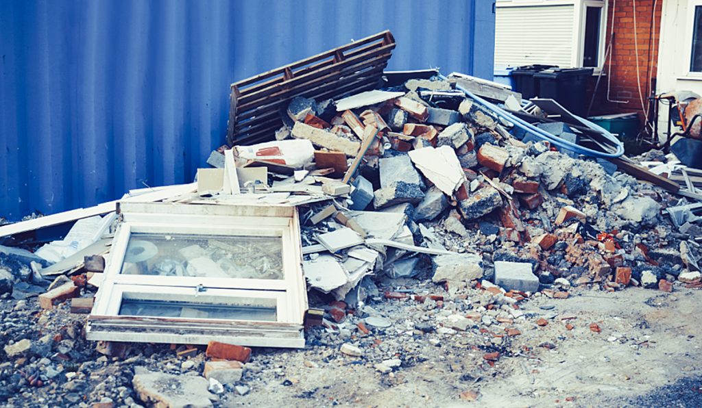 A pile of construction waste outside, against a fence