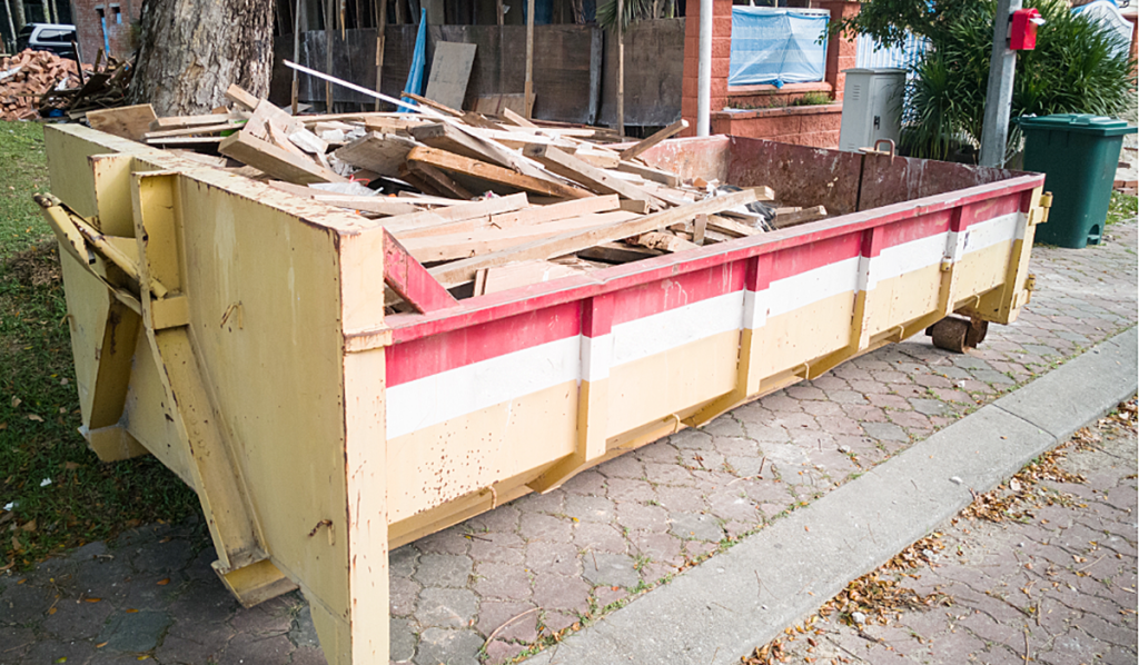 Large builders skip bin filled with timber and demolition waste outside a residential construction site.
