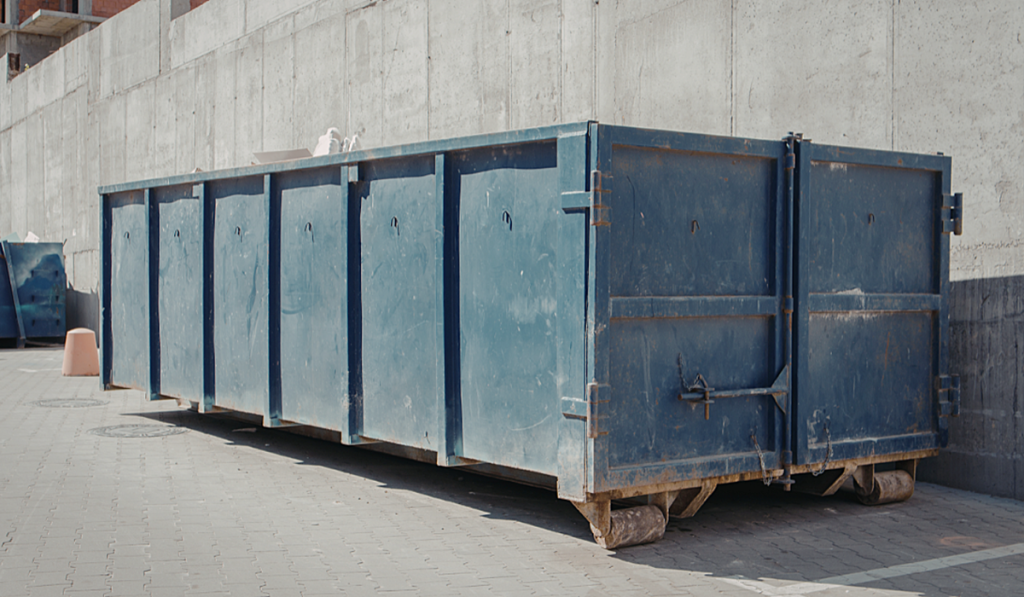 Large commercial waste skip bin positioned outside an industrial building for business waste collection.